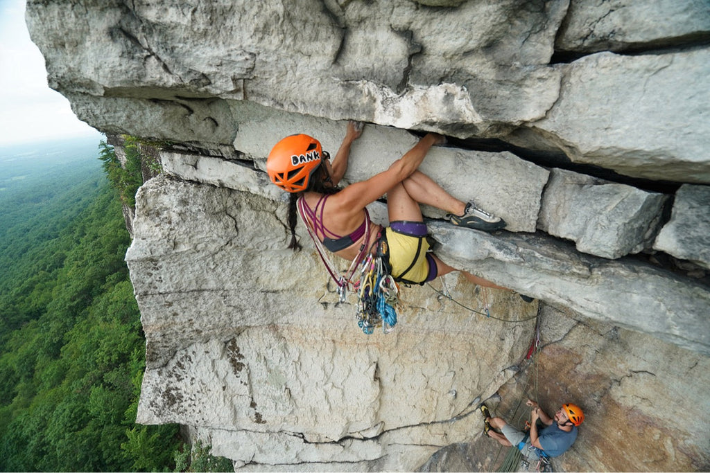 Têra Kaia ambassador and female rock climber Kathy Karlo leading a trad route in her TOURA basewear top outdoor sports bra