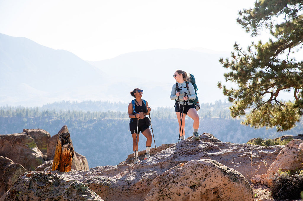 The real cost of sustainable outdoor clothing. Two women hiking in outdoor clothing discussing sustainability.